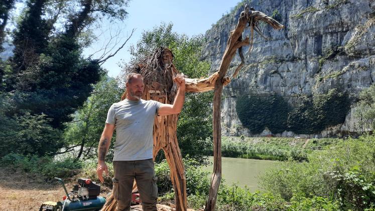 L'artista Merzi con la sua scultura di legno