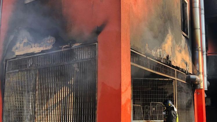 Gli inquilini del palazzo tentano di spegnere l’incendioIl fumo salito fino ai balconi degli appartamentiUn vigile del fuoco entra nel magazzino bruciato